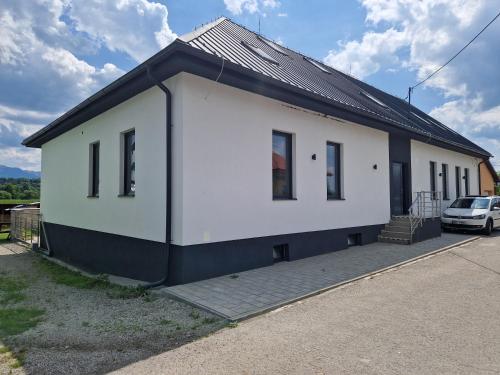 a white house with a car parked in front of it at apartmán TATRANKA in Vlašky