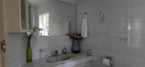 un bagno piastrellato bianco con lavandino e specchio di Bozi Abode a Kempton Park