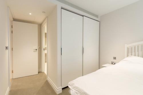 a bedroom with white walls and a white bed at Stylish 2 Bed Flats Near US Embassy in London