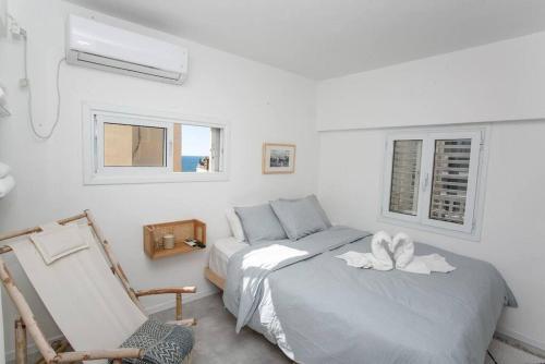 Prime Location 2BR Beach Flat في تل أبيب: غرفة نوم بيضاء بسريرين وكرسي