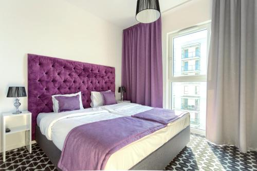 - une chambre avec un grand lit et une tête de lit violette dans l'établissement Apartamenty Vola Residence, à Varsovie