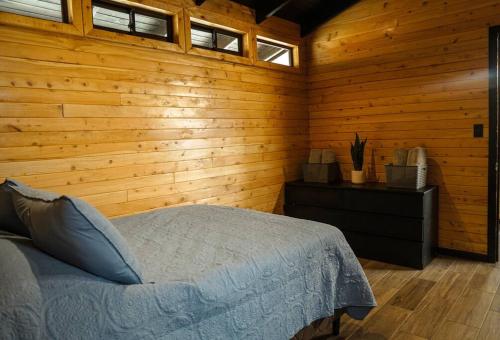 a bedroom with a bed and a wooden wall at Casa Nogal, Santa María de Dota 