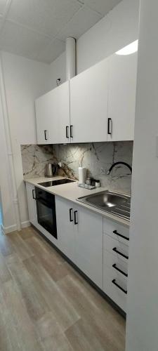 a kitchen with white cabinets and a sink at Apartamenty Częstochowa in Częstochowa