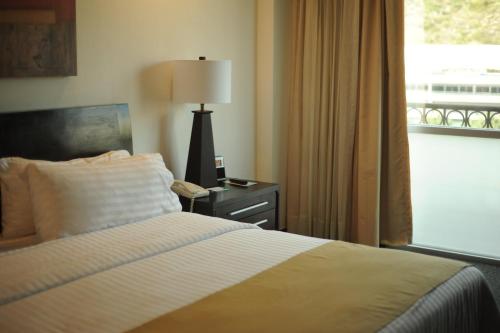 a bedroom with a bed and a lamp and a window at Holiday Inn Monterrey Valle by IHG in Monterrey