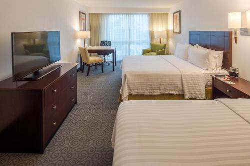 a hotel room with two beds and a flat screen tv at Holiday Inn Monterrey Valle by IHG in Monterrey
