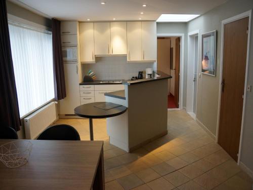 a kitchen with white cabinets and a table in it at Hotel Du Soleil in Knokke-Heist