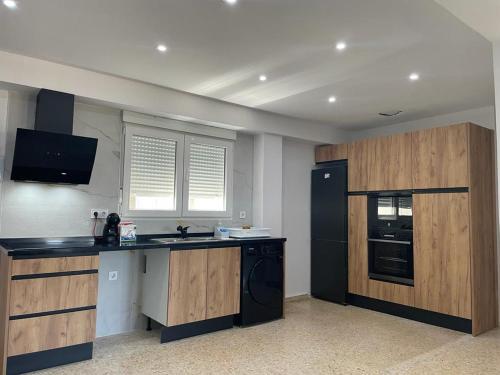 a kitchen with wooden cabinets and a black refrigerator at UIM Mediterraneo Emilio Llopis Wifi in Sagunto