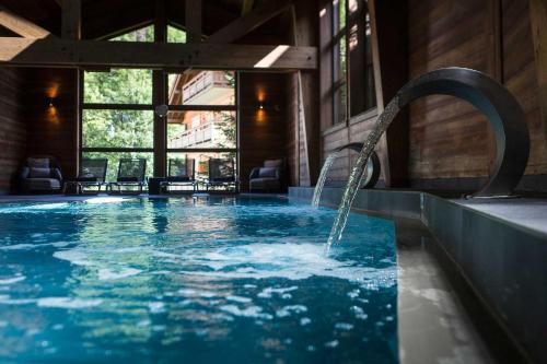 - une piscine avec une fontaine dans un bâtiment dans l'établissement Au Coeur du Village, à La Clusaz