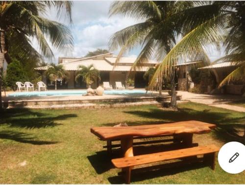 a picnic table in the grass next to a pool at Casa LUXO Guaibim in Guaibim