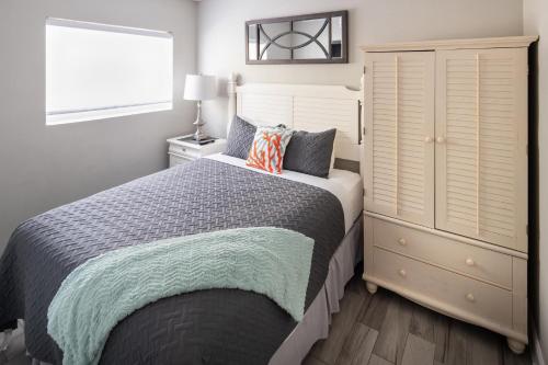 a bedroom with a bed and a dresser and a window at Emerald on the Water - Formerly Belleair Beach Club in Clearwater Beach
