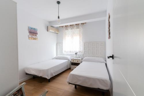 Un dormitorio con dos camas y una ventana. en Casa Moreda, en Almería