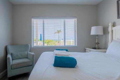 a bedroom with a bed and a chair and a window at Emerald on the Water - Formerly Belleair Beach Club in Clearwater Beach