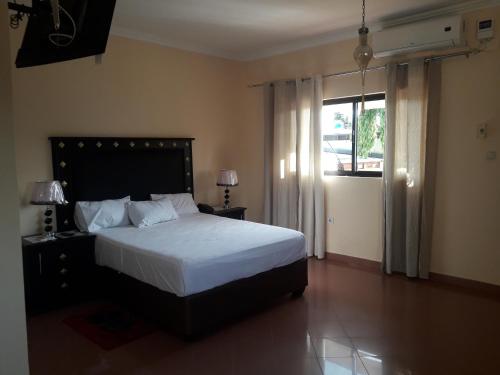 Un dormitorio con una cama grande y una ventana en Agentour Guesthouses, en Luanda