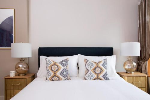 a bedroom with a white bed with pillows and two lamps at The Bakery by The Butler Collection in Arundel