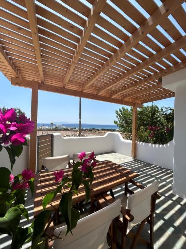 un patio con pergolato in legno, tavolo e sedie. di Marikos House, Pyrgaki Alyko Naxos a Spiaggia di Aliko
