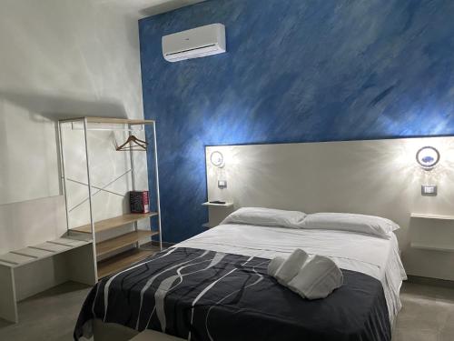 una camera con un letto con una parete blu di B&B Akoya Capo Vaticano a Capo Vaticano