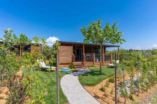 a house in the middle of a garden with a pathway at Fornella Camping & Wellness family resort in San Felice del Benaco