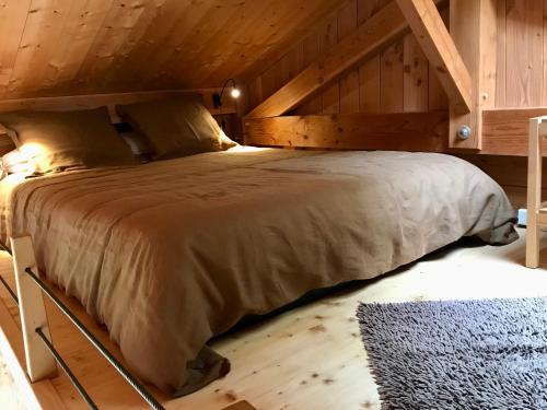 una camera con un grande letto e un soffitto in legno di Gîte Le Mazot de Vouan a Saint-André-de-Boëge