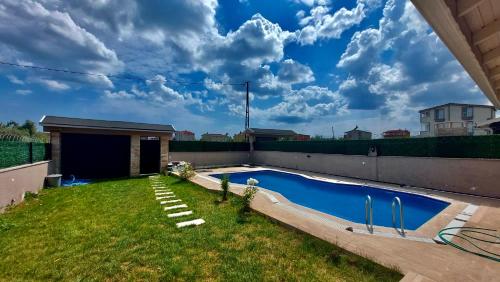 a backyard with a swimming pool and a yard with grass at Marmara luxury villa in Marmaraereglisi