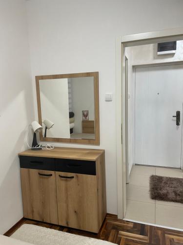 un miroir au-dessus d'une commode en bois à côté d'une porte dans l'établissement Stan u centru, Loznica, à Loznica