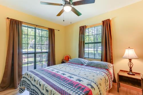 a bedroom with a bed with a ceiling fan and windows at Pools and Ski Access Lackawaxen Cottage with Deck! in Lackawaxen