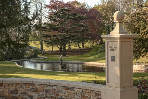 a stone pillar in front of a pond in a park at Farlam Hall Hotel & Restaurant in Brampton