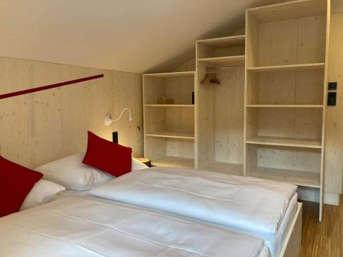 a bedroom with a white bed with red pillows and shelves at Horská chata Smědava in Weissbach
