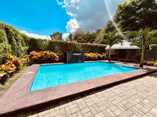 a swimming pool in a garden with a fence at Cabañas del Norte in Fortuna