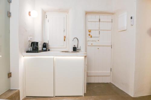 eine Küche mit weißen Schränken und einem Waschbecken in der Unterkunft Naos Suites in Vóthon