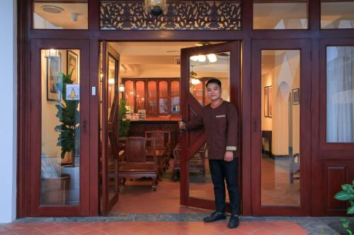 mężczyzna stojący w drzwiach domu w obiekcie Phongsavath Boutique Hotel w mieście Wientian