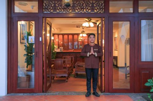 Una donna in piedi davanti a una porta di Phongsavath Boutique Hotel a Vientiane