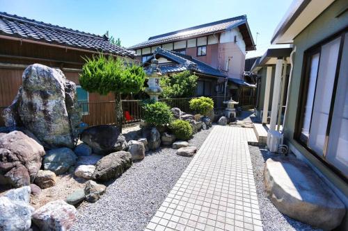 una pasarela de piedra frente a una casa con rocas en 貸別荘せせらぎ, en Taga