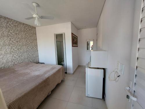 a bedroom with a bed and a refrigerator in it at Suíte Praia na casa da Berenice in Caraguatatuba