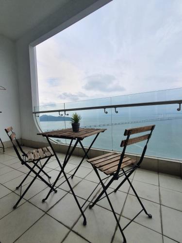 a table and two chairs in front of a large window at Seaview Condo 10pax #10minQueensbay #15minSpice in Bayan Lepas