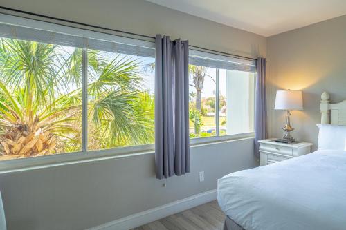 a bedroom with a bed and a window with a palm tree at Emerald on the Water - Formerly Belleair Beach Club in Clearwater Beach
