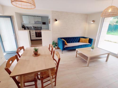 un salon avec une table et un canapé bleu dans l'établissement Maison 50m2 - 2 chambres - Jardin, à Fontaine-Étoupefour