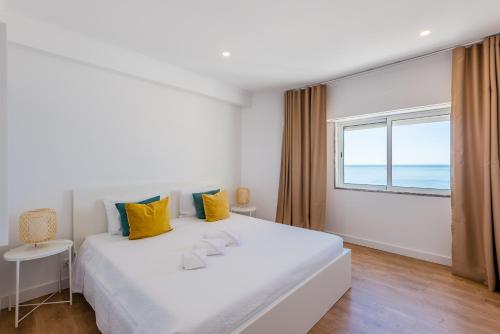 una camera bianca con un grande letto e una finestra di Vista Mar a Quarteira