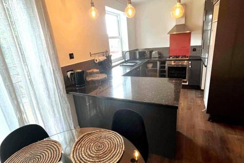 a kitchen with a counter and a table with chairs at Luxury, Spacious 1 Bedroom Flat in South Norwood