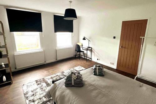 a bedroom with a bed and a chair and windows at Luxury, Spacious 1 Bedroom Flat in South Norwood
