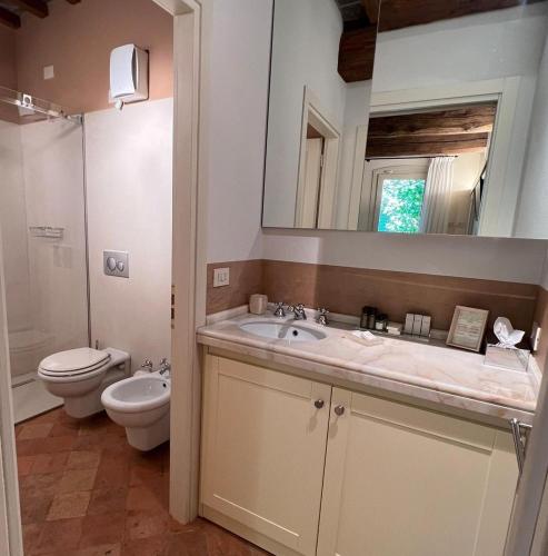 a bathroom with a sink and a toilet and a mirror at Le Case Di San Vitale Easy in Ravenna