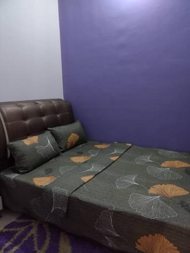 uma cama num quarto com uma parede roxa em Teratak HZ Homestay 2 em Kuantan
