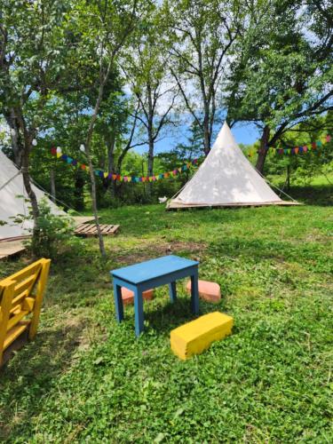 a picnic table and a tent in a field at Karavani in Ambrolauri