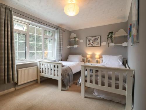 a bedroom with two beds and two windows at Church Cottage in Diss