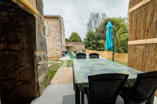 eine Terrasse mit einem Tisch, Stühlen und einem Sonnenschirm in der Unterkunft Le gîte de Romain in Sanvensa