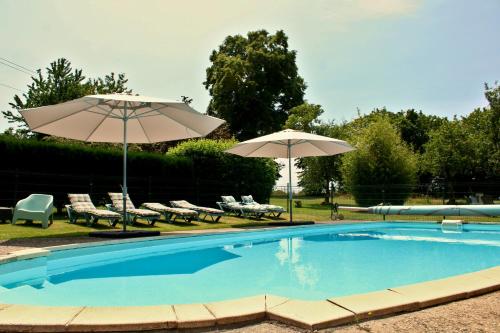 a swimming pool with two umbrellas and lounge chairs at The Alpaca B&B in Chaleix