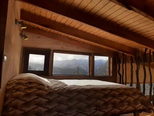 a bed in a room with a large window at Cabaña entre Bosque y Cordillera in Lonquimay