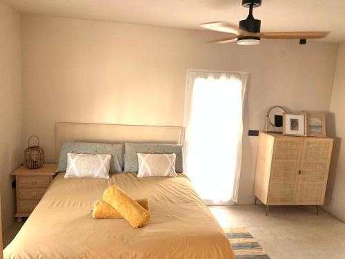 Villa AURA 500 metros de la playa في توري دي بيناغالبون: غرفة نوم عليها سرير وفوط صفراء