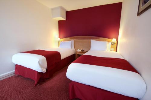 2 letti in una camera d'albergo con pareti rosse di Waterloo Hub Hotel and Suites a Londra