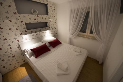 a small bedroom with a white bed with red pillows at Apartments Annya in Split