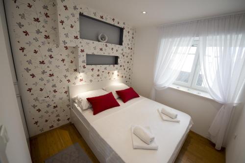 a small bedroom with a white bed with red pillows at Apartments Annya in Split